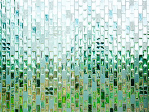 Close-up abstract seamless pattern texture of translucent bathroom glass window with the light and abstract natural green from outside.