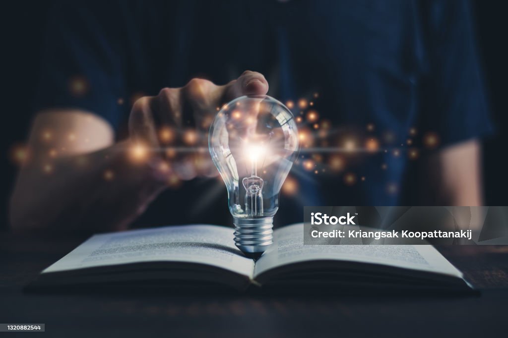 Glowing light bulb and book or text book with futuristic icon. Self learning or education knowledge and business studying concept. Idea of learning online class or e-learning at home. Learning Stock Photo