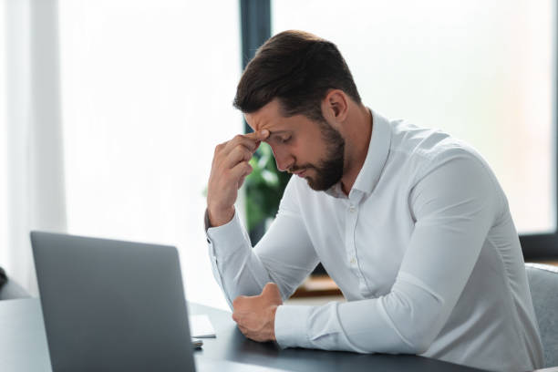 istock Young businessman massaging touching temples having severe headache while sitting at work table in office, suffering from migraine at work 1320889496