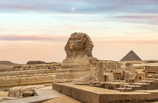 Egyptian Great Sphinx full body portrait with head, feet with all pyramids of Menkaure, Khafre, Khufu in background on a clear, blue sky day in Giza, Egypt, View of sphinx, giza plateau in desert