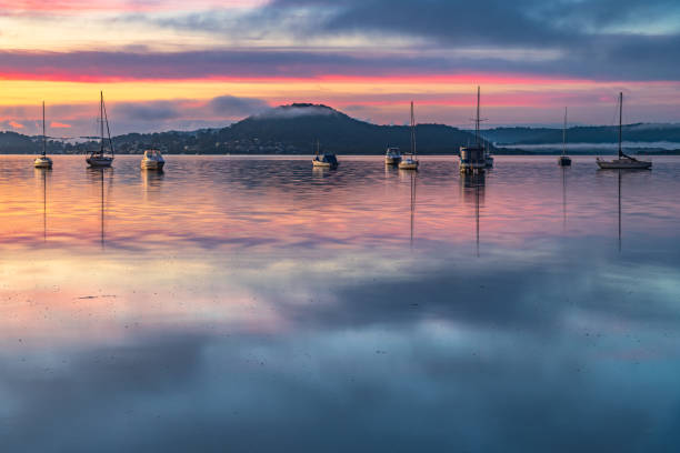 istock Sunrise waterscape with boats, light cloud and fog 1320891337