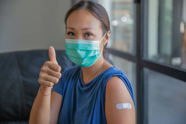 驕傲的亞洲婦女在接受 covid-19 疫苗後豎起大拇指 - covid 19疫苗 個照片及圖片檔