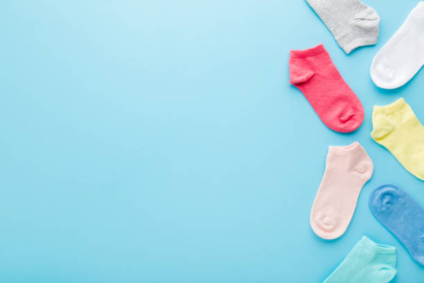 istock Colorful kid short socks on light blue table background. Pastel color. Closeup. Empty place for text. Top down view. 1320894449