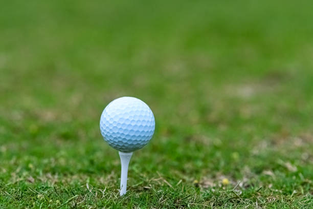 istock Golf ball on a tee with green background 1320896379