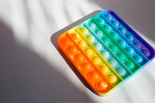 Photo of Colorful rainbow anti-stress fidget push pop it sensory toys for children. Simple dimple.
