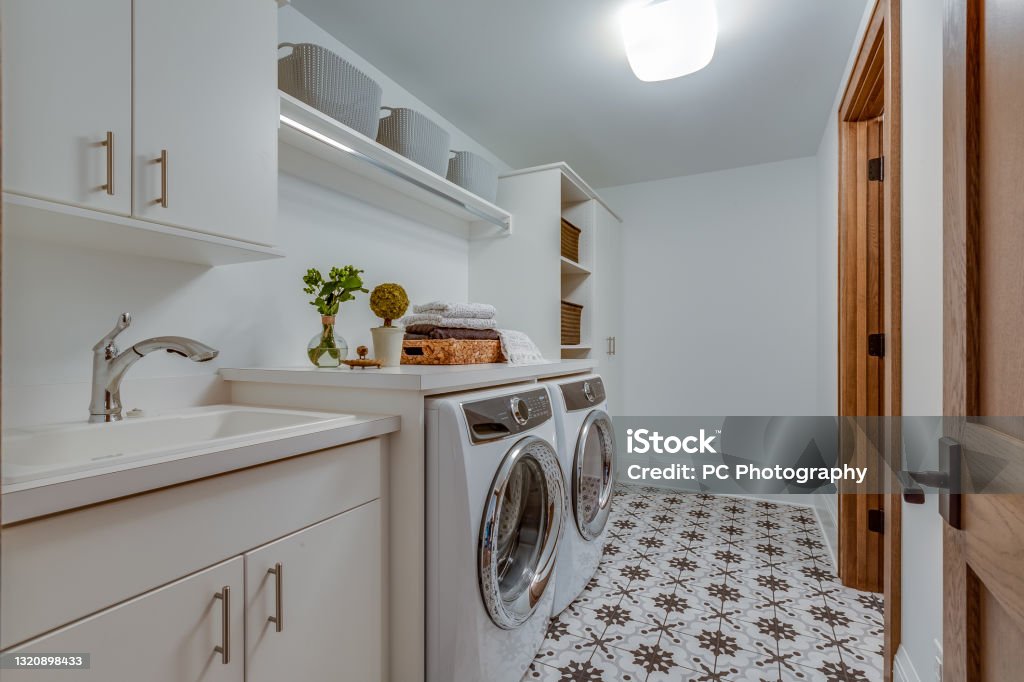 Patterned tile flooring in big laundry room New washer and dryer in utility room Utility Room Stock Photo