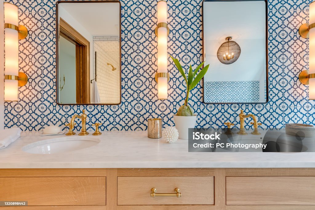 Blue and white patterned tile in bathroom with natural wood Stone countertops, bar of soap, and polished gold faucet Bathroom Stock Photo