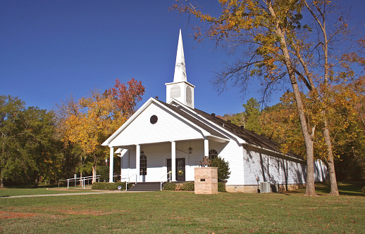 Rural Church in Autumn. White Church with leaves