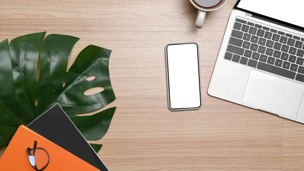 istock Mock up smart phone, laptop, notebook and coffee cup on wooden background. 1320899380