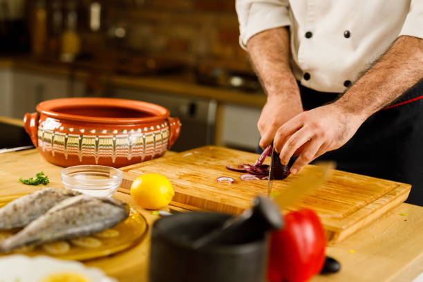 istock Unrecognizable chef cutting onion in the kitchen. 1320902718