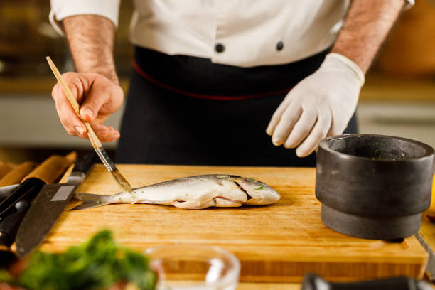 istock Unrecognizable chef brushing sea bream before making lunch in the kitchen. 1320903780
