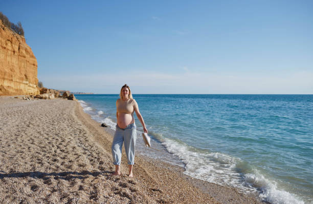 istock a pregnant woman standing on the seashore 1320904550