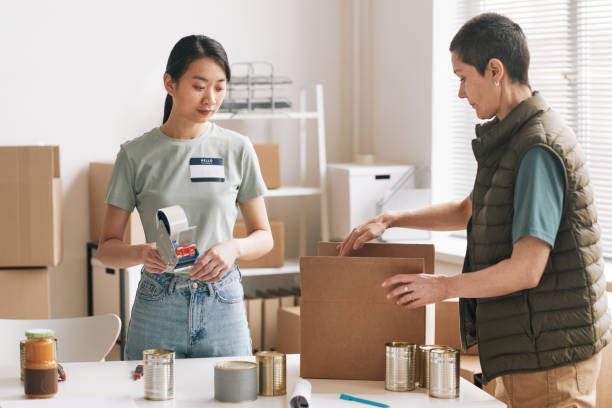 istock Two Women Packing Boxes with Charity Donations 1320910655