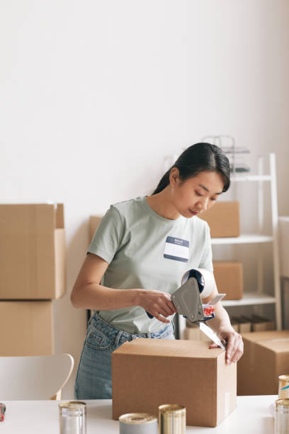 istock Woman Packing Boxes with Charity Donations 1320910658