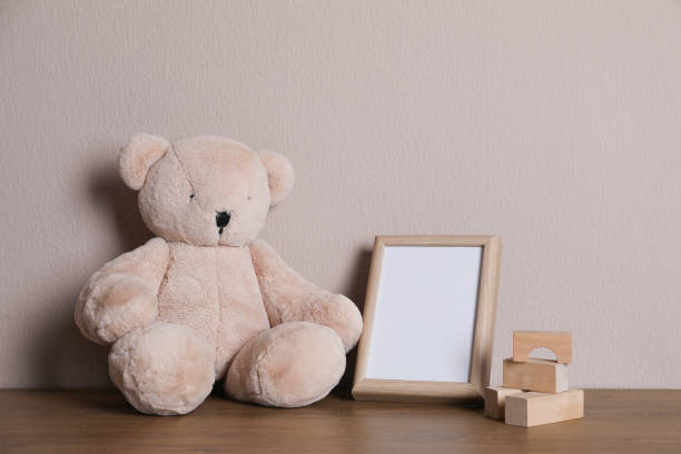 istock Empty photo frame, teddy bear and building blocks on wooden table near grey wall. Space for design 1320910788