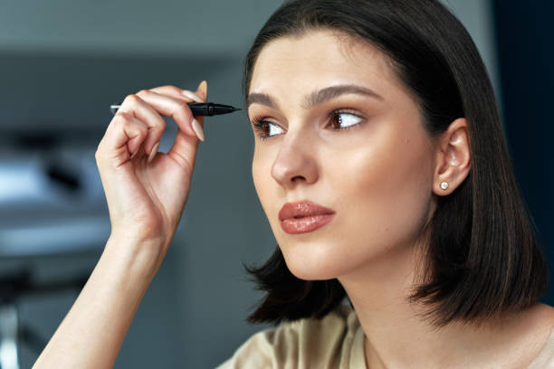 istock Closeup of a beautiful young woman combing her eyebrows during doing makeup. 1320910857