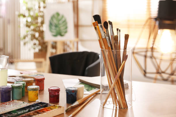 istock Paints and brushes on wooden table in art studio 1320911164