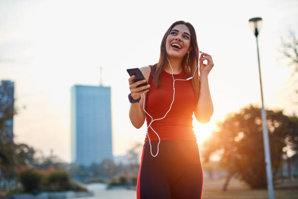 istock Modern young woman with cellphone making pause during jogging exercise. 1320911731