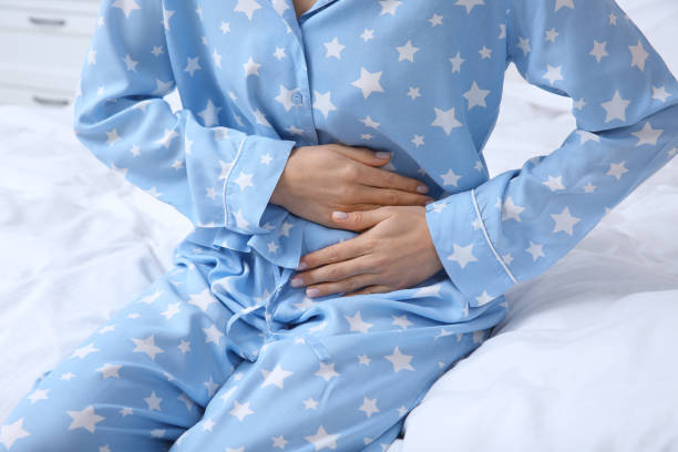 istock Young woman suffering from stomach ache on bed, closeup 1320911782