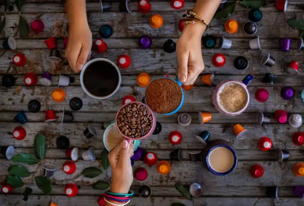 Photo of Coffee beans roasted in the mugs in the hands of two woman.