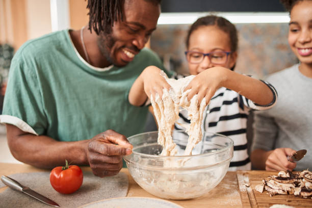 istock Father helping to his daughter adding and mixing ingredients in dough 1320914773