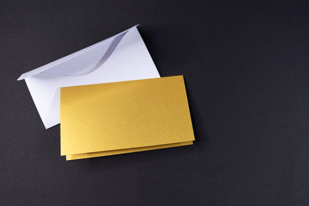 istock White envelope and invitation as golden square with blank surface on black background, mockup, space for text 1320917118