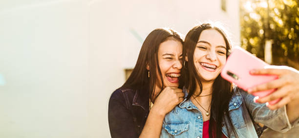 two happy young hispanic women together taking a selfie with copy space. friendship concept. young girls friends happiness. - diş telleri stok fotoğraflar ve resimler