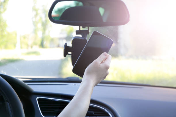 istock Woman inserting her cell phone in car phone holder 1320917384