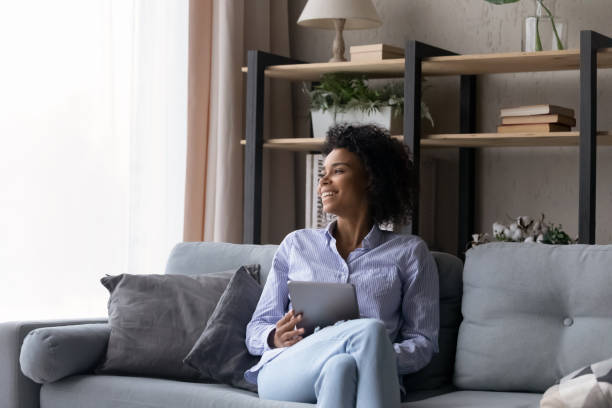 istock Smiling biracial woman use tablet look in distance thinking 1320917608