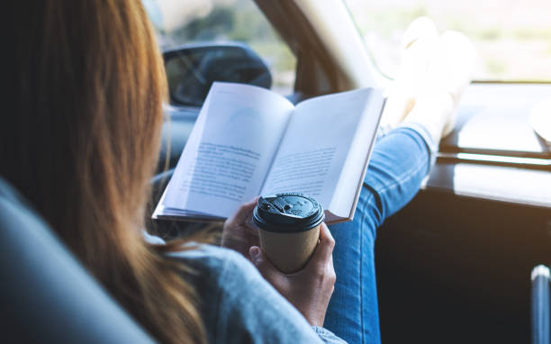 istock A woman reading book and drinking coffee in the car 1320918507