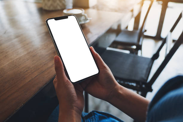 istock a woman holding mobile phone with blank white desktop screen in cafe 1320918514