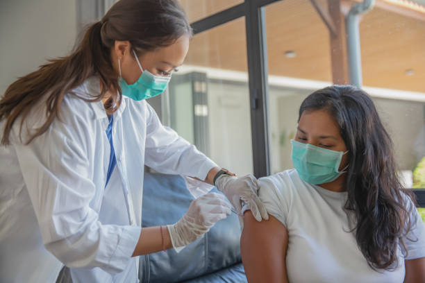 médico do sudeste asiático dando a uma paciente a injeção da vacina covid-19. - southeast asian ethnicity fotos - fotografias e filmes do acervo