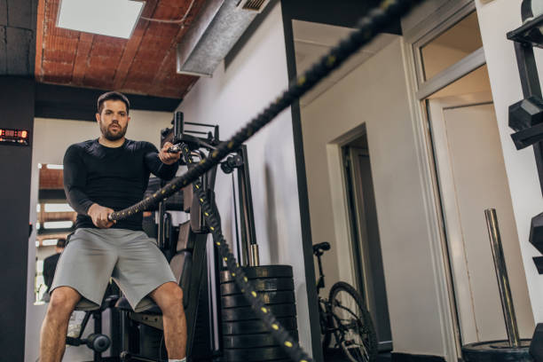 istock Man exercising with battle ropes in gym 1320923071