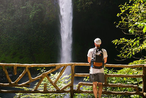 Tourist looking at the La Fortuna Waterfall in Costa Rica. The waterfall is located on the Arenal River at the base of the dormant Chato volcano.