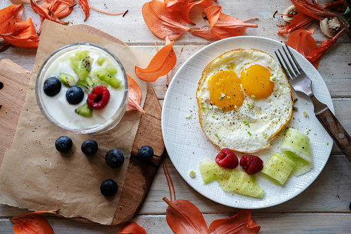 healthy breakfast: yogurt, fried egg and berry fruits on dining table