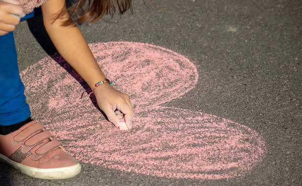 carino bambino disegna con gesso all'aperto, ora legale, gesso. messa a fuoco selettiva. - little girls sidewalk child chalk foto e immagini stock