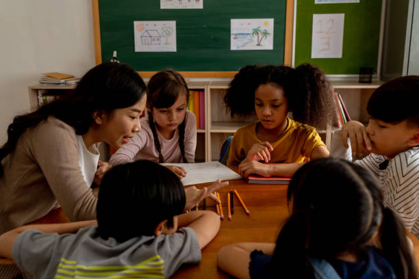 Asian school teacher assisting students in classroom Young woman working in school helping children with arithmetic, learning about mathematics, counting. Asian school teacher assisting multiethnic students in classroom math teacher stock pictures, royalty-free photos & images