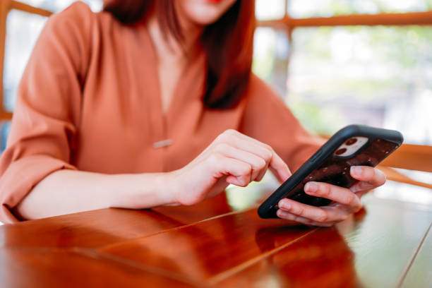 Hands of young woman using smartphone in cafe stock photo