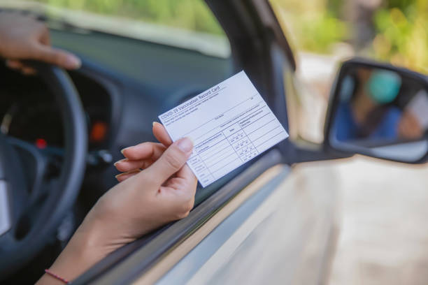 istock Unrecognizable Female Driver Holding a COVID-19 Vaccination Record Card 1320924619