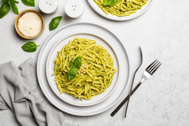 włoskie danie - trofie al pesto, makaron z sosem pesto z liści bazylii, twardy ser, orzeszki piniowe, czosnek, oliwa z oliwek.  lekkie tło, widok z góry. - pesto sauce italian culture pine nut photography zdjęcia i obrazy z banku zdjęć