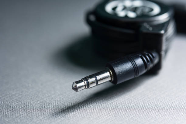 istock Mini jack cable. Black Audio connector. 3.5 mm plug with a black wire, shot large on a gray background. Background for music and computer equipment. 1320926402