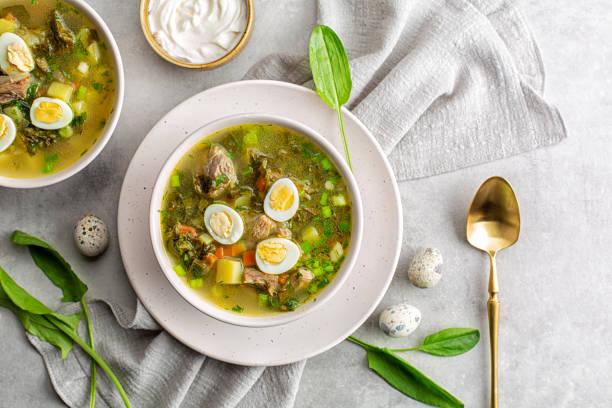 frühlingsessen, sauerampfersuppe aus rinderbrühe, sauerampferblätter, hart gekochte wachteleier, kartoffeln, karotten, petersilie. hellgrauer hintergrund. kopieren sie den speicherplatz. - wachtelei stock-fotos und bilder