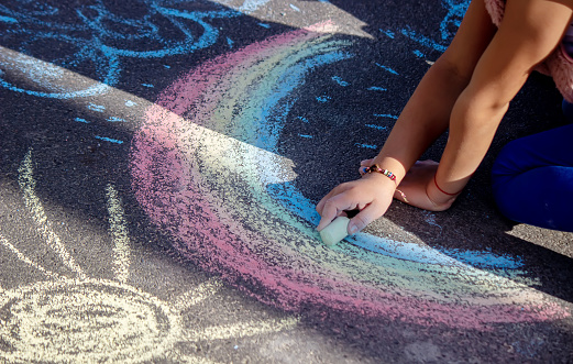 Cute little child draws the sun with chalk outdoors, summer time, chalk. Selective focus. Nature