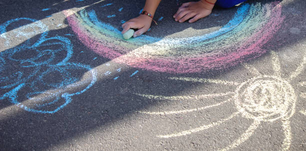 istock Cute little child draws the sun with chalk outdoors, summer time, chalk. Selective focus. 1320928037