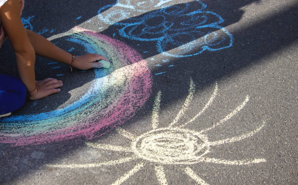 istock Cute little child draws the sun with chalk outdoors, summer time, chalk. Selective focus. 1320928039