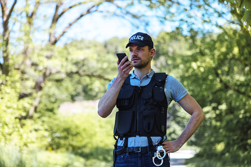 Policeman Using Smart Phone On Crime Scene In Nature