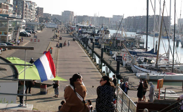 Restaurant, Land Vehicle, Docked Boat, Building Exterior, People Sitting Down, Walking Around, Standing, Looking Around, Buying Food During Summer Season At Scheveningen Beach Harbour In South Holland The Netherlands Europe