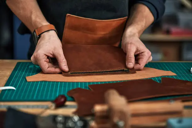 Skilled leather manufacture worker cutting some samples. close up shot