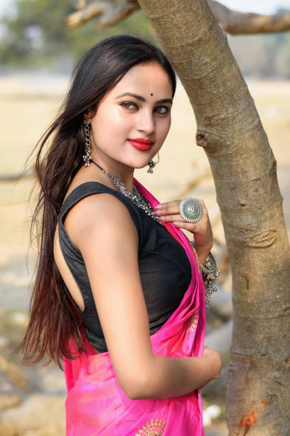Outdoor portrait of very beautiful straight haired young attractive woman wearing pink saree and light jewellery and posing fashionable in blurred background. Lifestyle and Fashion. stock photo