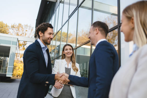 Happy male executives meeting and handshaking on the street stock photo